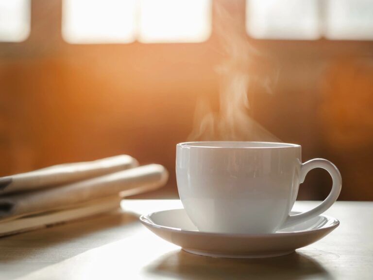 coffee cup with newspaper on the table, coffee shop background, warm tone